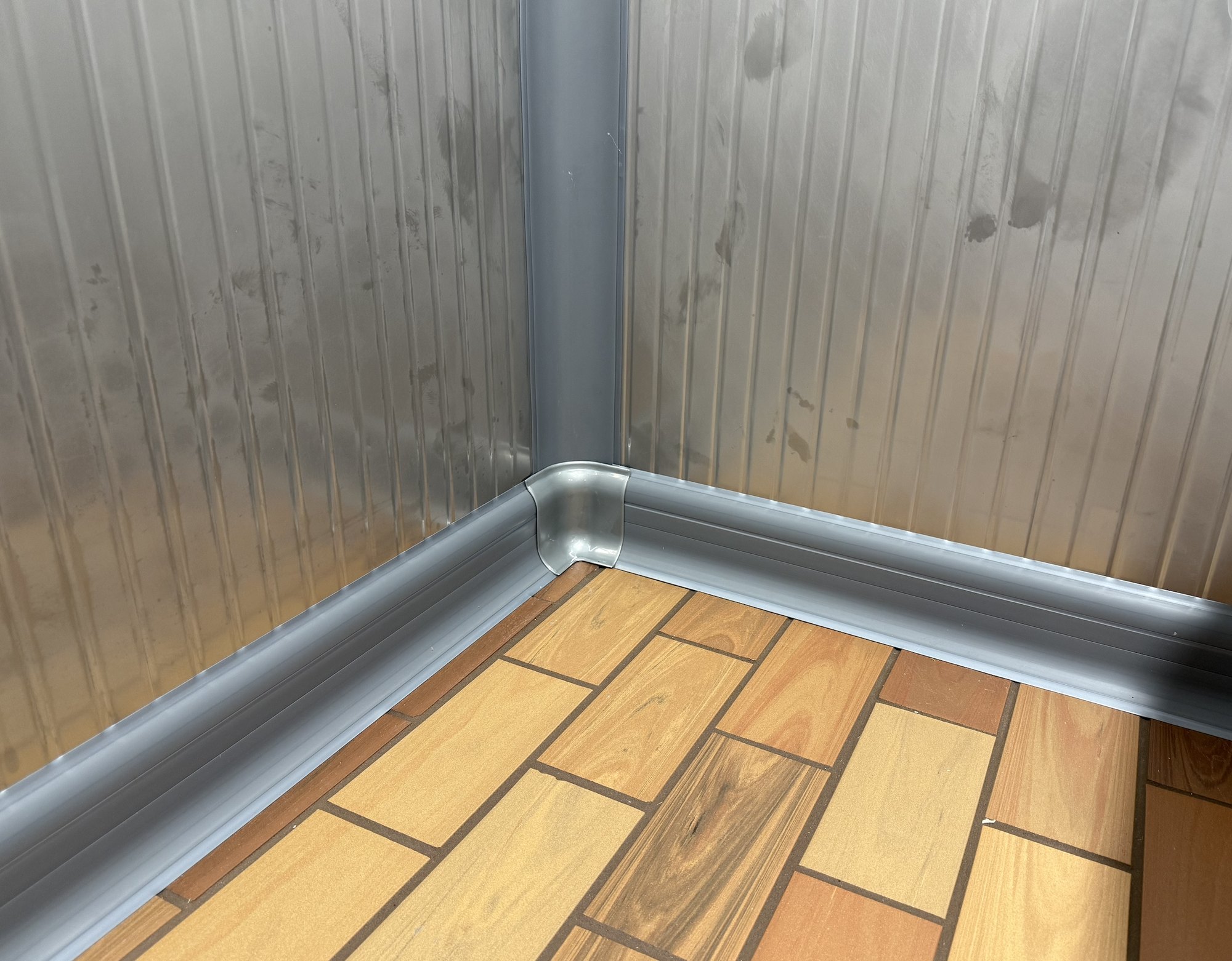 CoRound Basic PVC cove base in Stainless Steel Gray 9023 along two walls of stainless steel panels, with an inside corner piece where the floor base meets a vertical profile in the wall corner